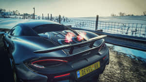 黑色McLaren跑車在雪地路邊排氣管噴火，日落時分。