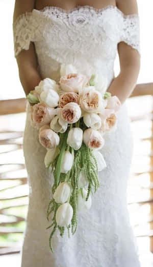 身穿蕾絲婚紗的新娘手持柔和的粉白花束。 — 鬱金香 壁紙