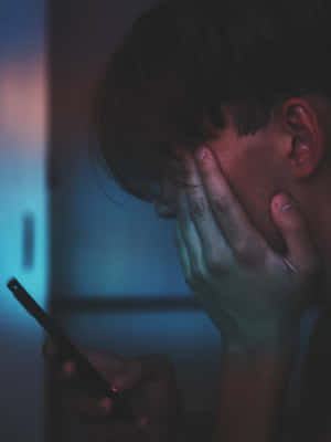 人在昏暗藍光下手機遮臉