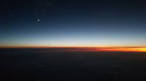 雲層上方新月和星星的暮色天空鳥瞰圖。