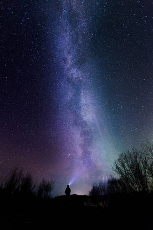 夜晚站在山丘上，銀河系下的人