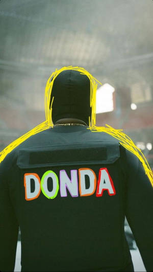 一個人穿著黑色連帽衫，上面有彩色字母和黃色塗鴉寫著「DONDA」。