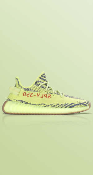 淡綠色背景上，帶有深藍色圖案和紅色文字的青檸綠色Yeezy 350運動鞋。