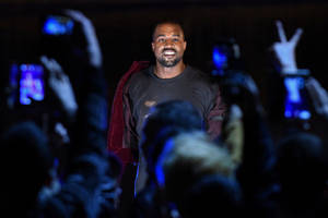 Kanye West 在演唱會上微笑，粉絲舉起手機。