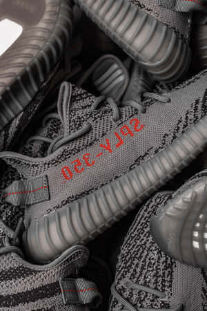 一堆灰色 Yeezy Boost 350 運動鞋，帶有紅色品牌細節。