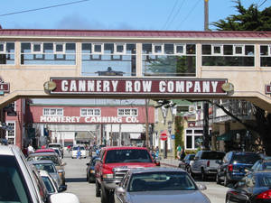 藍天下，坎納里街（Cannery Row）上停著汽車和歷史建築。 — 加州 壁紙
