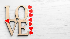 白色木質背景上帶有紅色心形的木製LOVE字母。