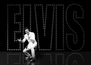 埃爾維斯·普雷斯利在明亮燈光下跳舞，身後有「ELVIS」標誌。 — 貓王 壁紙