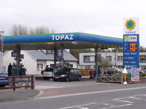 一個陰天，Topaz 加油站有汽車在藍色遮篷下加油。