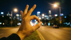 夜晚在城市街道上做出OK手勢，伴隨著明亮的燈光。
