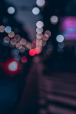 夜晚的城市燈光在黑暗的街道上模糊成發光的圓圈。