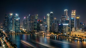 夜晚充滿活力的城市天際線，燈火通明的摩天大樓和水面上的光跡。