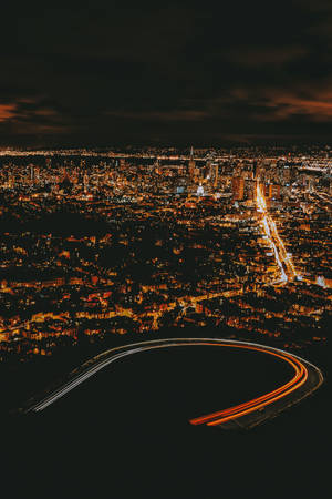 從高空拍攝的城市夜景照片，燈光閃爍，帶有彎曲的高速公路線條。