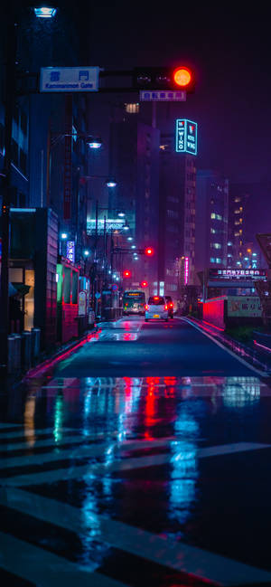 霓虹燈在潮濕的路面上反射，一條下雨的日本城市街道夜景。 — 霓虹 iPhone 壁紙