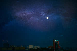 星空下的城市景觀，有明亮的月亮和銀河。