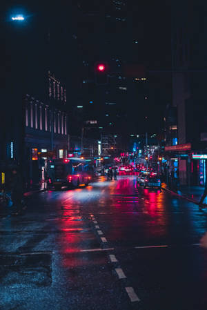 夜間城市街道，濕漉漉的路面反射霓虹燈光和交通。