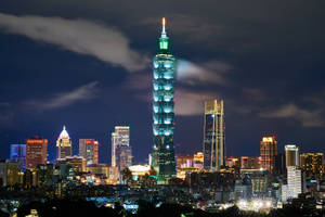 台北101摩天大樓在城市燈光中閃耀著綠色光芒的夜景。