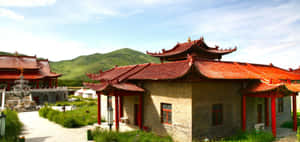 傳統中式寺廟建築群，紅瓦屋頂和石徑，位於翠綠山巒之中。 — 日落大道 壁紙