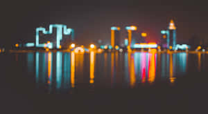 夜間城市燈光在水中的倒影，帶有散景效果 — 天際線 壁紙