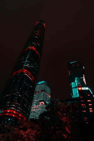 高聳摩天大樓在夜間被紅色和青綠色燈光照亮。