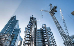 城市中晴朗藍天下的現代摩天大樓和建築起重機。