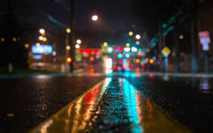 夜雨中的城市街道，模糊的燈光反射在濕漉漉的路面上。 — Mac GIF 壁紙