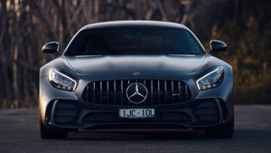 灰色梅賽德斯-AMG GT跑車在道路上，後面有樹木的前視圖。