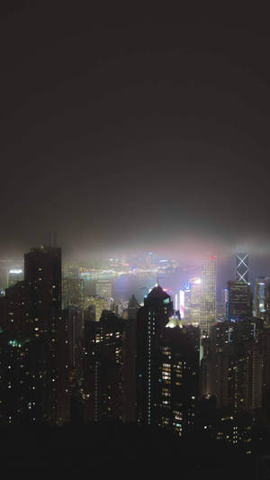 夜晚的城市天際線，燈火通明的建築物和迷濛的氛圍。