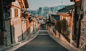 傳統韓國房屋排列在寧靜的街道上，遠處是現代化的城市天際線。 — 夜景城市 壁紙