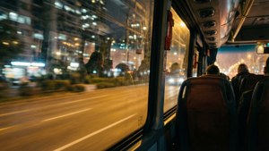 乘客乘坐巴士穿過夜晚的城市，窗外燈光模糊。