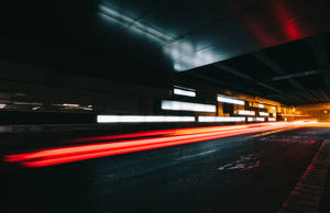 夜晚黑暗的城市隧道地下通道中移動車輛的紅色光條。