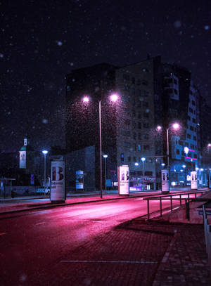 夜晚，在明亮的街燈下，雪落在安靜的城市街道上。 — 紫色 iPhone 壁紙