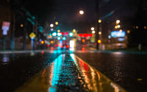 城市街道上的夜雨，模糊的交通燈光映照在濕漉漉的路面上。
