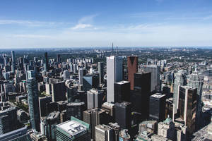 從高空俯瞰密集的現代城市，高聳的摩天大樓和清澈的藍天。
