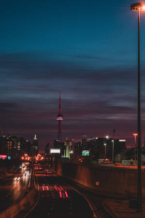 夜晚的城市高速公路，帶有流動的車燈線條和背景中的CN塔。