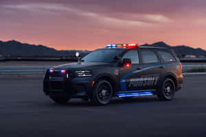 黑色警用SUV在黃昏的高速公路上閃著警燈，靠近山脈。