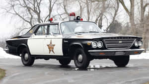 復古黑白警長車停在雪路上，周圍有光禿樹木。