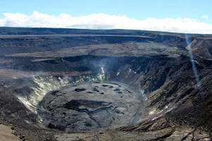 藍天下有蒸汽通風口和龜裂土地的火山口。