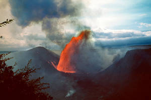 火山爆發，在陰雲密佈的天空下噴出明亮的橙色熔岩和黑煙。