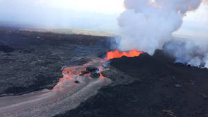 熔岩從火山流出，穿過黑暗的景觀，煙霧升騰。