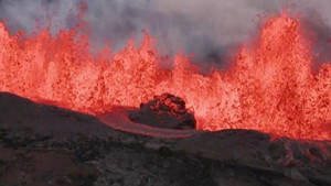 熔岩從火山口噴發，帶有明亮的紅色熔岩和黑煙。