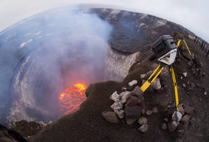 三腳架上的相機俯瞰火山口內發光的熔岩湖。