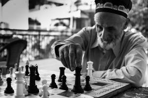 一位長者在戶外下棋的黑白照片。