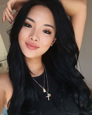 長黑髮女性輕觸頭髮微笑。