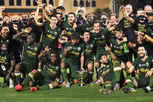 足球隊在夜晚的草地上舉起獎盃慶祝勝利。 — 冠軍 壁紙