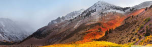 晴朗天空下，白雪覆蓋的山峰和秋色山坡。