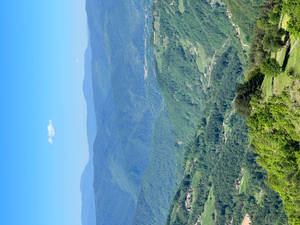 起伏的綠色山脈，點綴著小村莊和蜿蜒的道路，在清澈的藍天下。