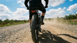 騎單車的人在碎石路上騎胖胎單車，在晴天揚起灰塵