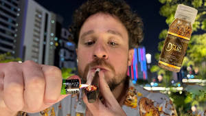 男人在夜晚的城市中點燃大麻煙，有霓虹燈和一個漂浮的香料瓶。