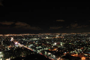 多雲天空下，密集燈光的城市夜景，街道和建築物閃閃發光。